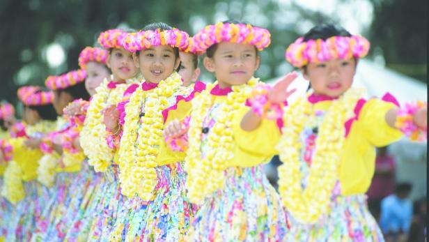 Eine Reihe junger Mädchen in traditionellen hawaiianischen Hula-Kostümen tanzt.