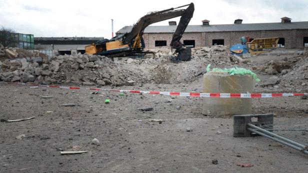Ein Bagger steht auf einer Baustelle vor einem Gebäude.