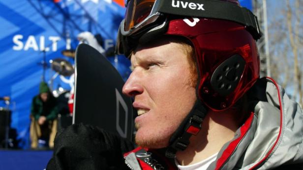 Ein Snowboarder mit rotem Helm und Uvex-Brille blickt nachdenklich zur Seite.