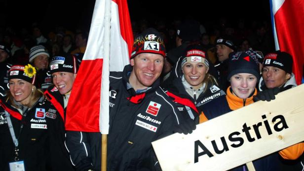 Eine Gruppe österreichischer Sportler posiert mit der österreichischen Flagge und einem Schild mit der Aufschrift „Austria“.