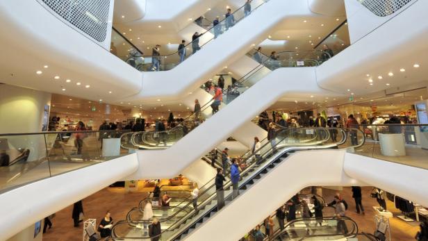 Mehrere Rolltreppen in einem belebten, mehrstöckigen Einkaufszentrum.
