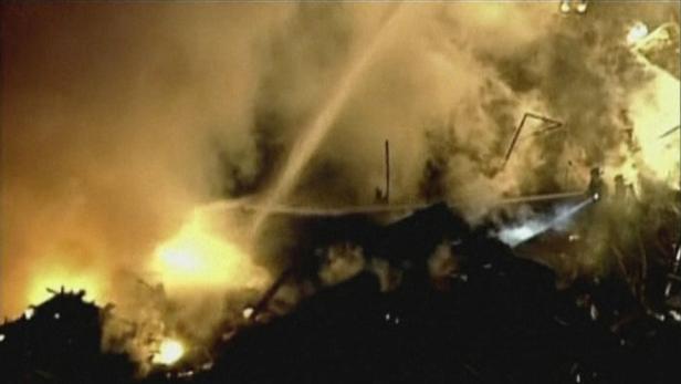 Ein Feuerwehrmann löscht ein brennendes Gebäude.