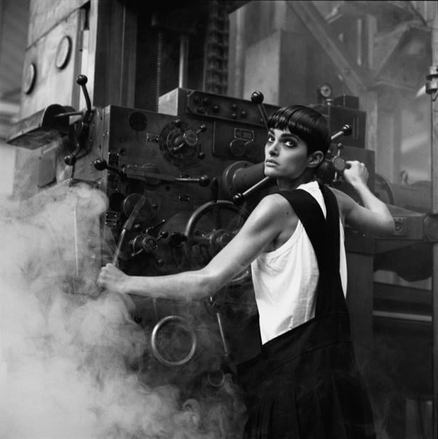 Eine Frau in Arbeitskleidung bedient eine große Industriemaschine in einer Fabrikhalle.