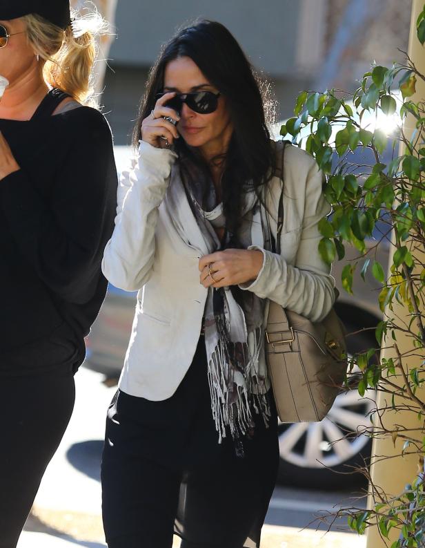 Courteney Cox mit Sonnenbrille und Schal auf der Straße.