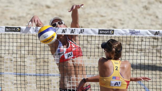 Eine Beachvolleyballspielerin schlägt den Ball über das Netz.
