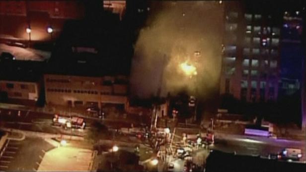 Ein Gebäude steht in Flammen, während Feuerwehrleute am Abend versuchen, das Feuer zu löschen.