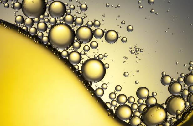 Goldene Blasen unterschiedlicher Größe schweben in einer Flüssigkeit.