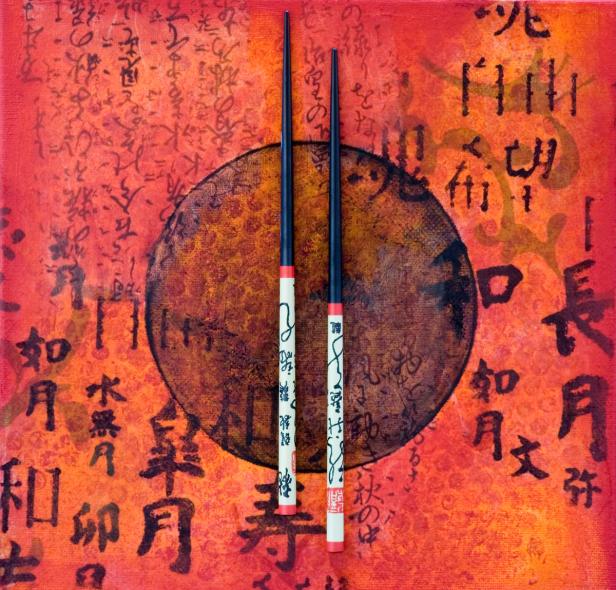Zwei verzierte Essstäbchen vor einem abstrakten Hintergrund mit japanischen Schriftzeichen.