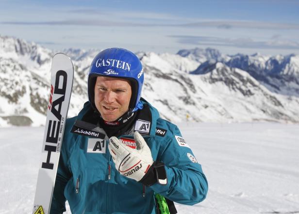 Ein Skifahrer mit Helm und Skiern vor einer verschneiten Berglandschaft.
