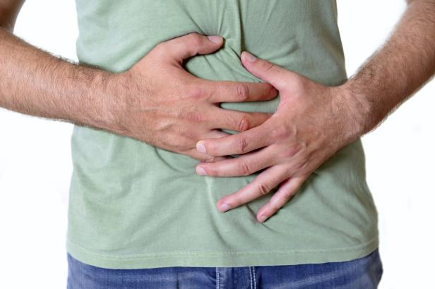 Ein Mann hält sich mit beiden Händen den Bauch.