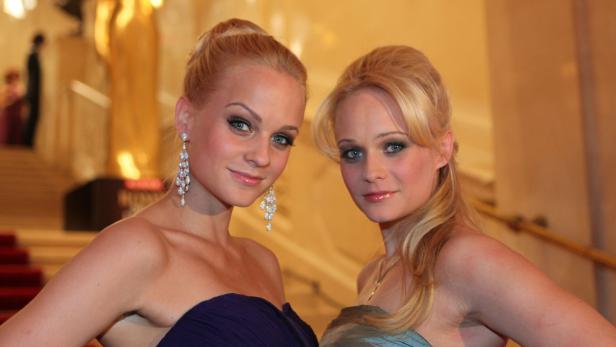 Zwei blonde Frauen in Abendkleidern posieren für ein Foto.