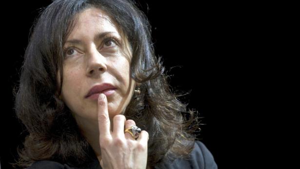 Eine Frau mit dunklen Haaren denkt nach, den Finger an die Lippen gelegt.