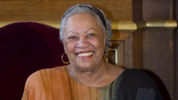Die lächelnde Schriftstellerin Toni Morrison sitzt auf einem Stuhl.