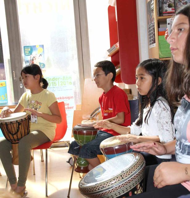 Eine Gruppe Kinder sitzt und spielt auf verschiedenen Trommeln.
