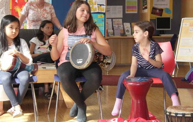 Eine Gruppe von Mädchen sitzt und spielt auf verschiedenen Trommeln.