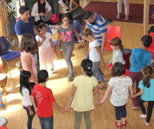 Eine Gruppe Kinder steht im Kreis und hält Händchen.