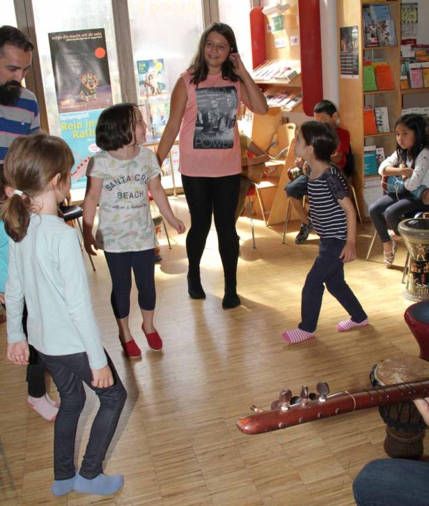 Eine Gruppe Kinder tanzt und musiziert in einem Raum.