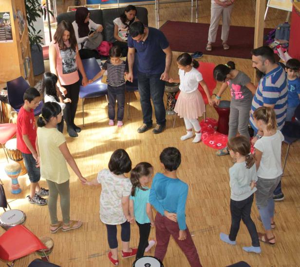 Eine Gruppe Kinder und Erwachsene steht im Kreis und hält Hände.
