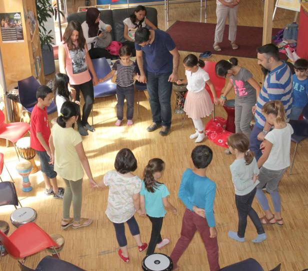 Eine Gruppe Kinder und Erwachsene steht im Kreis und hält Hände.