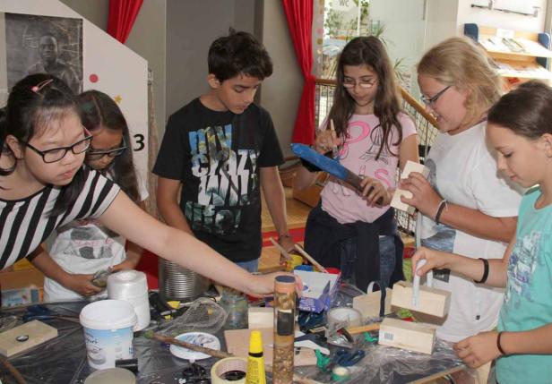 Eine Gruppe Kinder bastelt gemeinsam an einem Tisch mit verschiedenen Materialien.