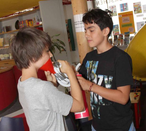 Zwei Jungen hantieren mit einem Trichter und einem Schlauch.