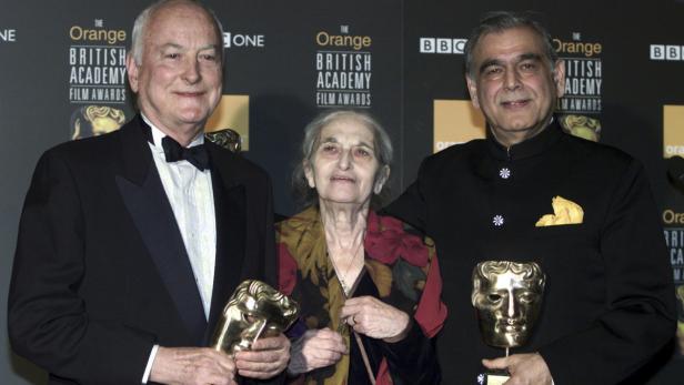 Drei Personen posieren mit BAFTA-Preisen vor einem Hintergrund der British Academy Film Awards.