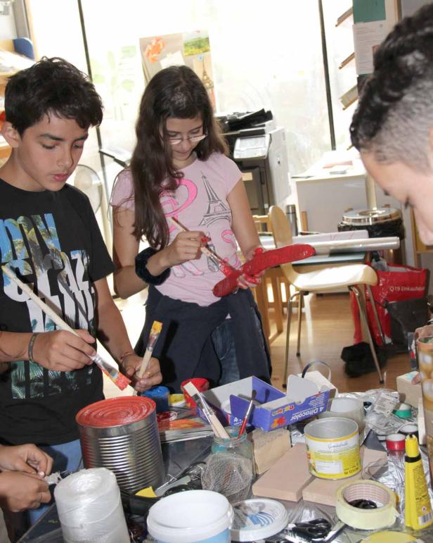 Eine Gruppe von Kindern bemalt Gegenstände in einem hellen Raum.