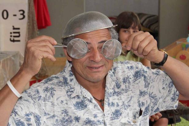 Ein Mann mit einem Sieb auf dem Kopf und zwei kleinen Sieben vor den Augen.