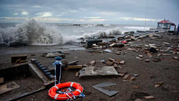 Ein zerstörter Strand mit Trümmern und einer Rettungsboje im Vordergrund.