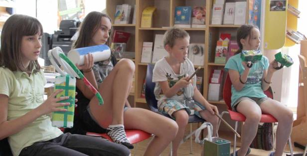 Eine Gruppe Kinder sitzt in einem Raum und bastelt mit verschiedenen Materialien.