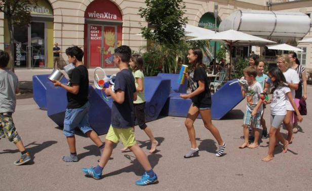 Eine Gruppe Kinder läuft barfuß oder mit Socken durch eine Fußgängerzone.