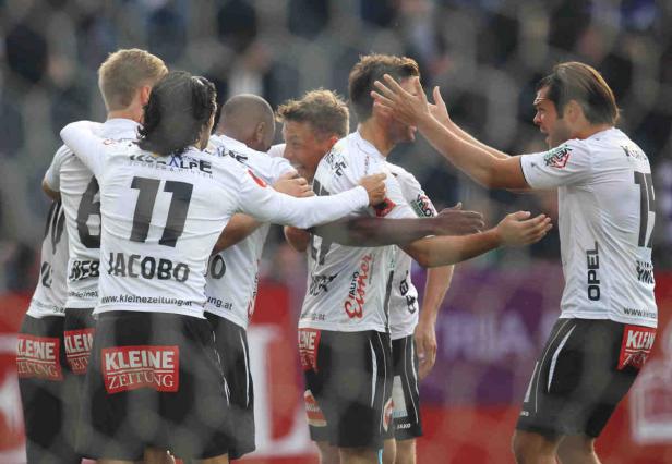 Eine Gruppe Fußballspieler in weißen Trikots feiert ein Tor.
