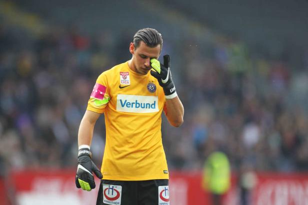 Ein Fußballtorwart wischt sich mit seinem Handschuh die Augen.