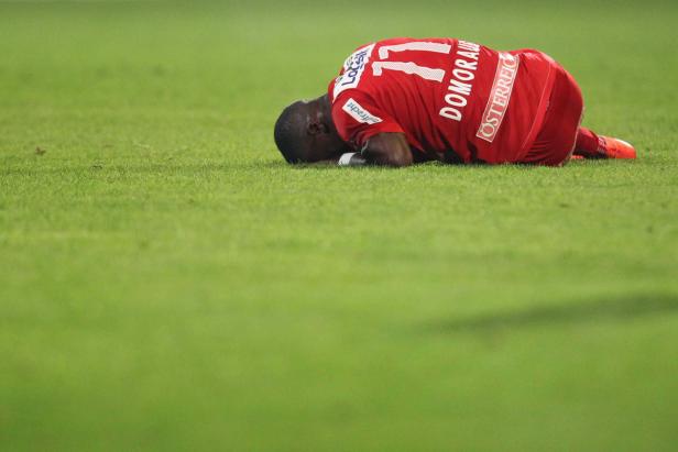 Ein Fußballspieler liegt enttäuscht auf dem Rasen.
