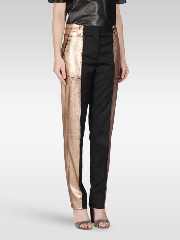 Eine Frau trägt eine Hose mit einem Bein aus schwarzem Stoff und einem Bein aus schimmerndem, roségoldenem Stoff.