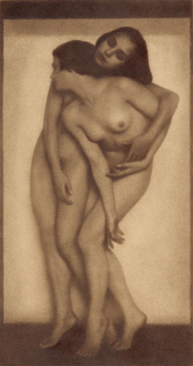 Zwei nackte Frauen umarmen sich in einem Sepia-Ton.