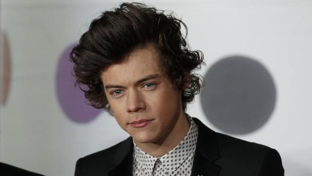 Porträt von Harry Styles mit dunklen, gewellten Haaren und einem schwarzen Anzug.