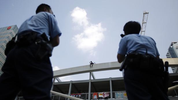 Zwei Polizisten beobachten eine Person, die auf einer Brücke sitzt.