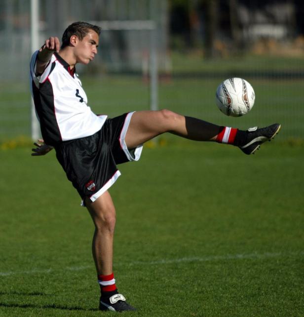 Ein Fußballspieler schießt einen Ball auf einem grünen Rasen.