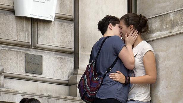 Zwei Frauen küssen sich vor einem Gebäude in Wien.