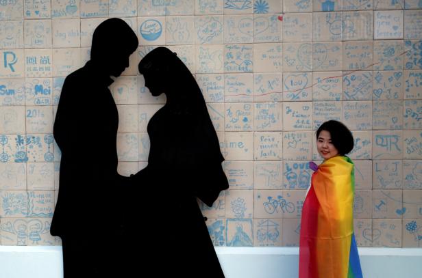 A participant poses next to a wedding studio during a LGBT pride parade to support same-sex marriage in Taipei