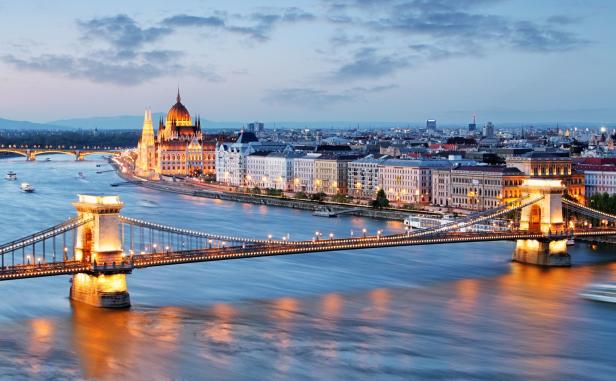 Die beleuchtete Kettenbrücke und das ungarische Parlament in Budapest bei Dämmerung.