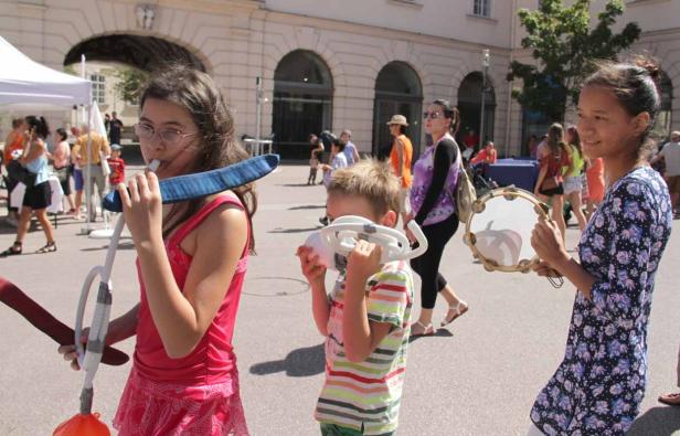 Eine Gruppe von Kindern spielt mit Musikinstrumenten auf einer belebten Straße.