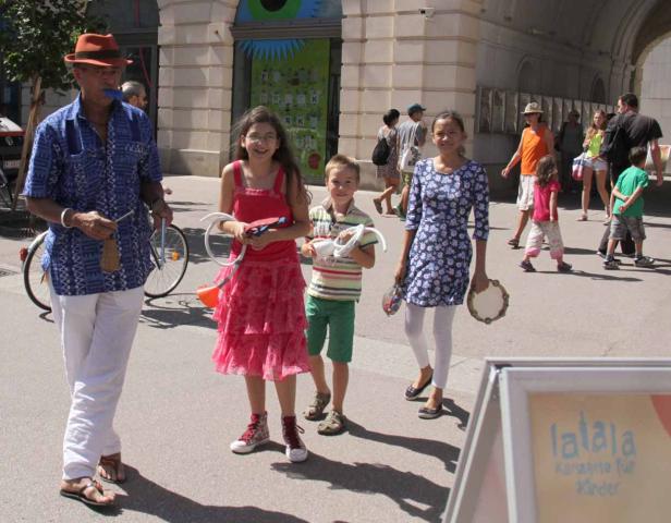 Eine Gruppe von Kindern und ein Mann mit Musikinstrumenten stehen auf einer Straße.