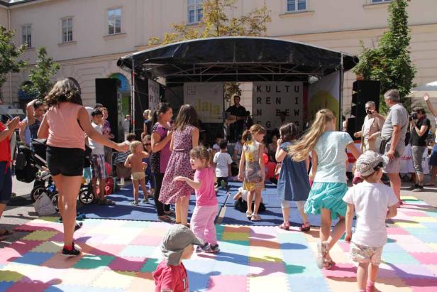 Kinder tanzen auf einer Bühne bei einer Open-Air-Veranstaltung.