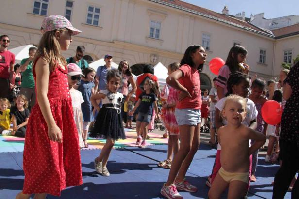 Eine Gruppe von Kindern tanzt und spielt im Freien.