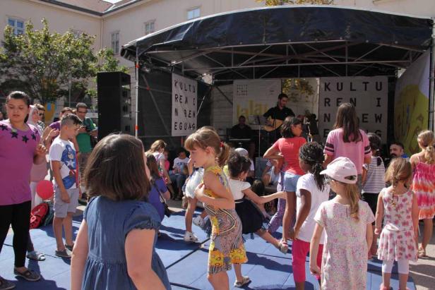 Eine Gruppe Kinder tanzt vor einer Bühne mit Musikern.