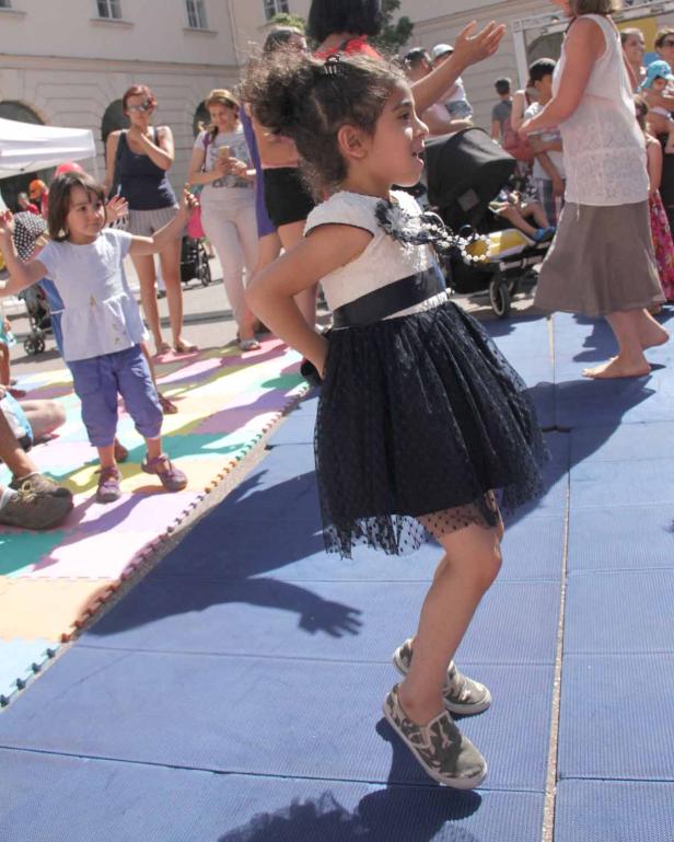 Ein junges Mädchen tanzt auf einer blauen Bühne im Freien.