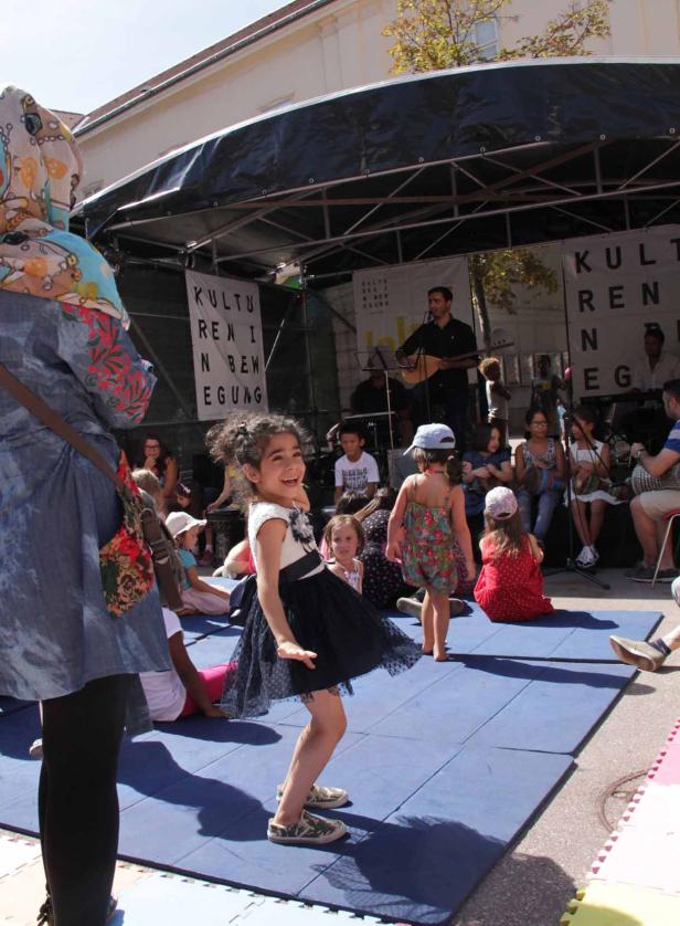 Ein Mädchen tanzt auf einer Bühne vor einer Gruppe von Zuschauern und Musikern.