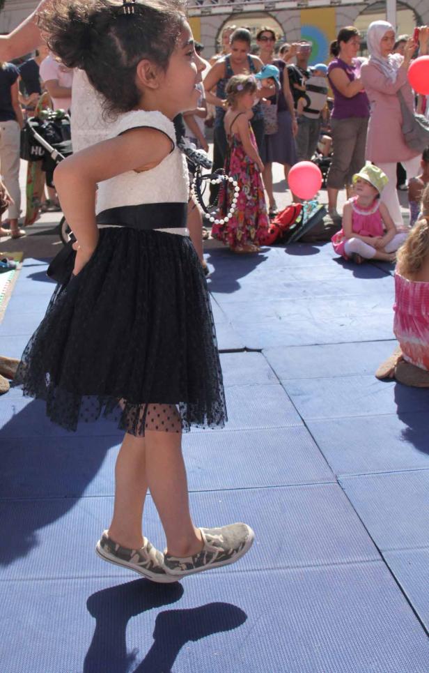 Ein junges Mädchen in einem Kleid steht auf einer blauen Oberfläche.